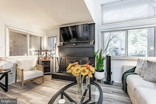 a living room with furniture a fireplace a flat screen tv and windows