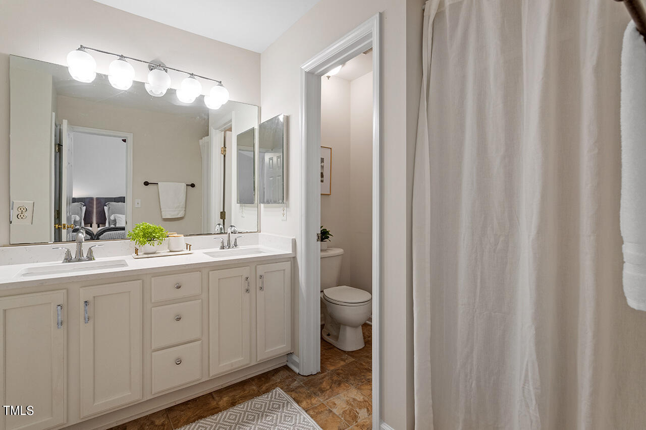 12601 Waterlow Park Lane Raleigh, NC 27614 - Photo 23 of 38 a spacious bathroom with a double vanity sink a toilet a mirror and a shower