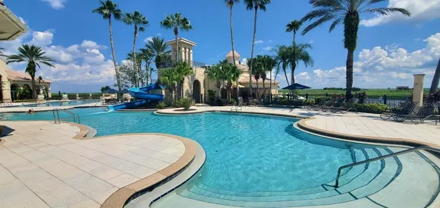 a swimming pool with outdoor seating yard and palm trees