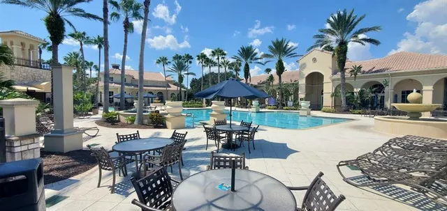 a view of a patio with couches table and chairs under an umbrella with a fire pit
