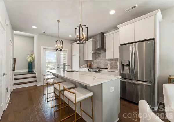 a kitchen with stainless steel appliances a refrigerator a sink dishwasher a stove and a dining table with wooden floor