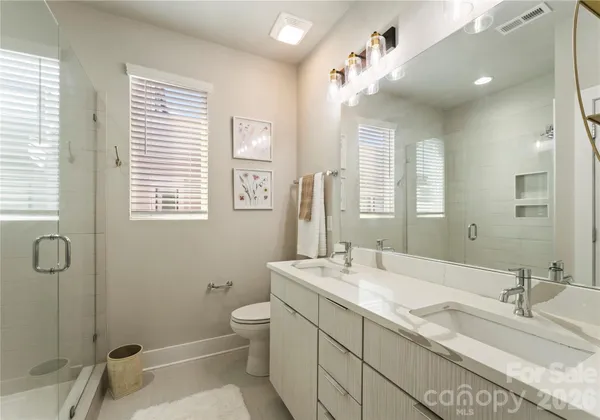 a bathroom with a granite countertop sink a toilet a mirror and shower
