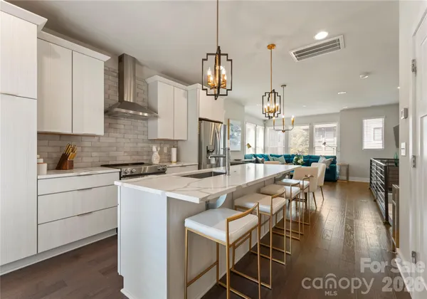 a very nice looking kitchen with granite countertop a table chairs stove and cabinets