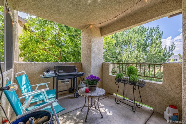 a balcony with couple of chairs and a potted plant