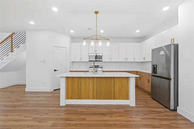 a kitchen with stainless steel appliances granite countertop a refrigerator a sink dishwasher a stove and a refrigerator with wooden floor