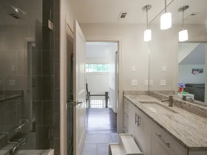 a bathroom with a granite countertop sink a mirror and a shower
