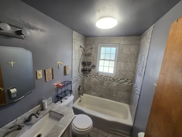 a bathroom with a bathtub shower sink vanity mirror and toilet