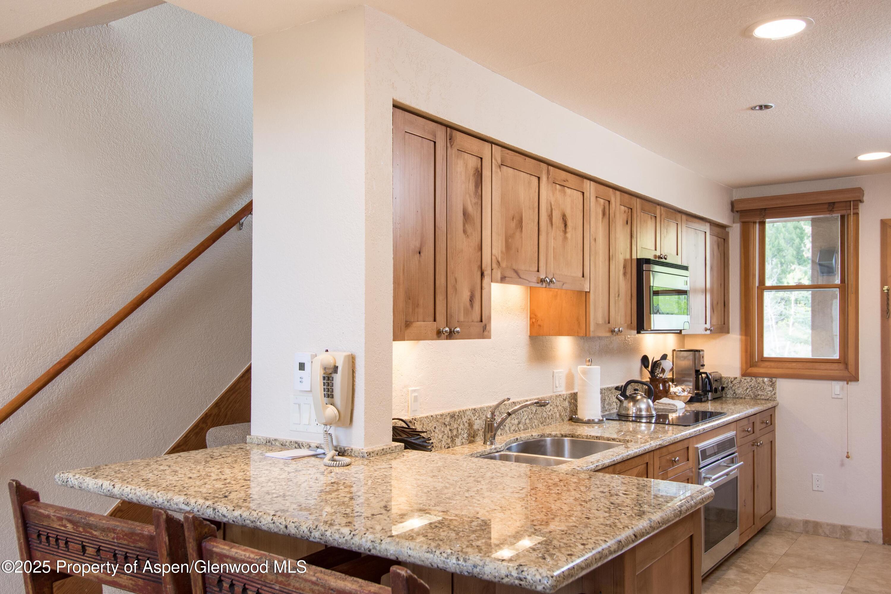 425 Wood Road, Unit 48 Snowmass Village, CO 81615 - Photo 17 of 41 a kitchen with granite countertop a sink and a window