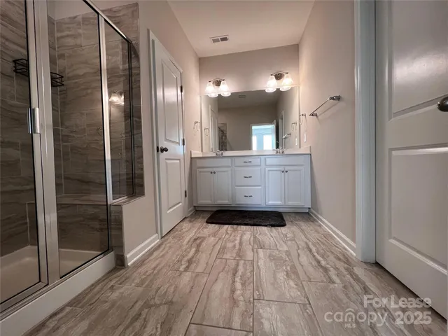 a large bathroom with a glass door shower and sink