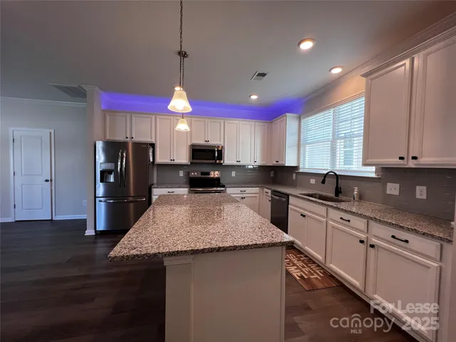 a kitchen with granite countertop kitchen island stainless steel appliances a sink stove top oven and granite counter top