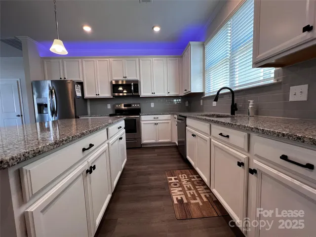a large kitchen with stainless steel appliances kitchen island granite countertop a sink counter space and cabinets