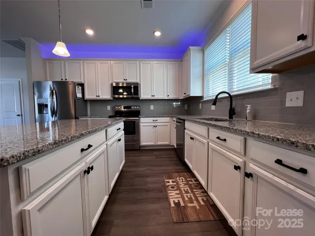 a large kitchen with stainless steel appliances kitchen island granite countertop a sink and cabinets