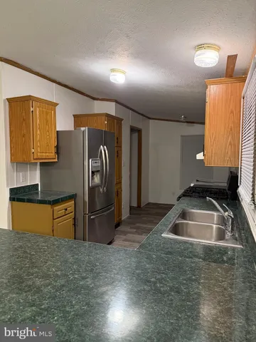 a kitchen with granite countertop a refrigerator and a sink