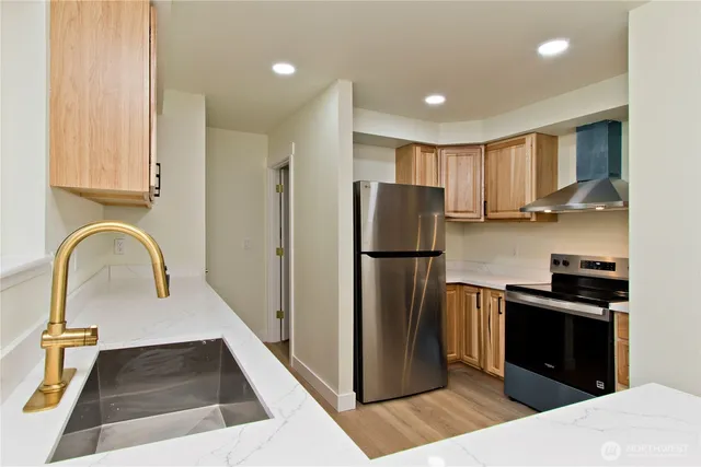 a kitchen with stainless steel appliances granite countertop a refrigerator a stove and a sink with wooden floor