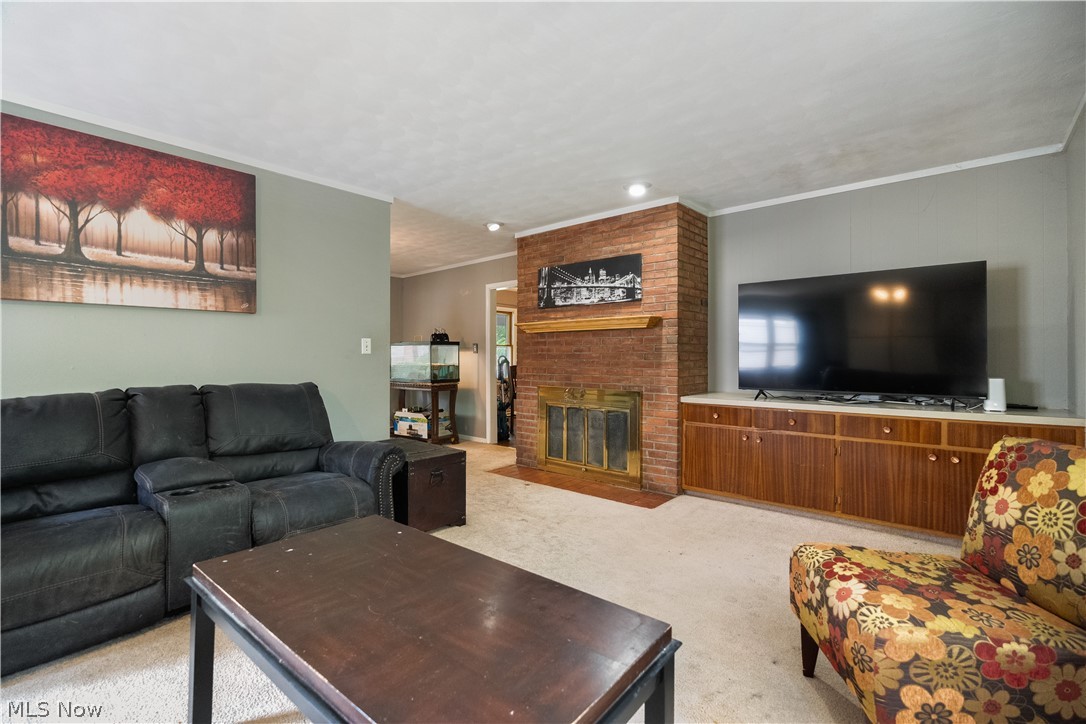 542 Garnette Road Akron, OH 44313 - Photo 9 of 24 Living area featuring a brick fireplace with a wood mantel, a built-in media console with wood-finish cabinetry, and light-colored carpeting