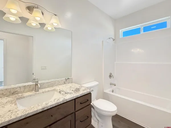 a bathroom with a granite countertop sink a toilet a mirror and bathtub