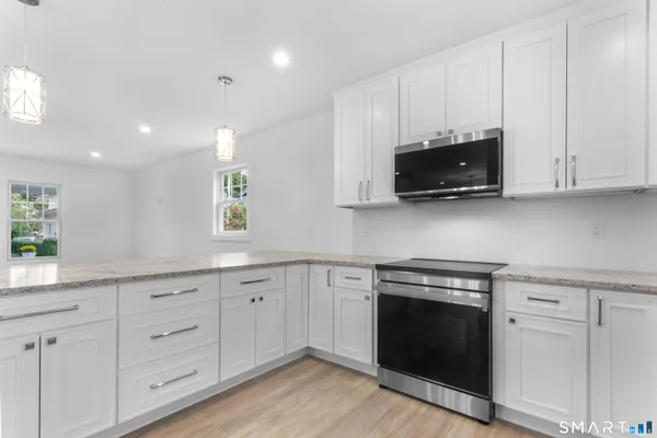 a kitchen with white cabinets and a stove with wooden floor