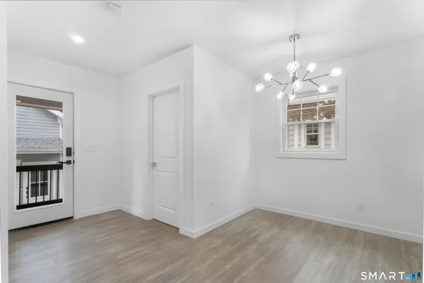 an empty room with wooden floor chandelier and windows