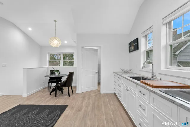 a large white kitchen with stainless steel appliances granite countertop a refrigerator and a sink
