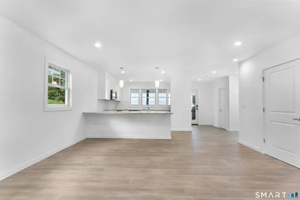 a view of kitchen with kitchen island a sink wooden floor and a refrigerator