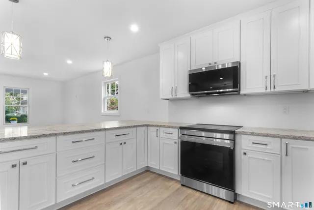 a kitchen with white cabinets and a stove with wooden floor