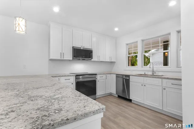 a kitchen with stainless steel appliances granite countertop a stove a sink and a microwave