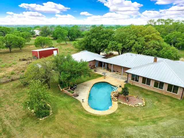 an aerial view of a house with swimming pool a yard and lake view