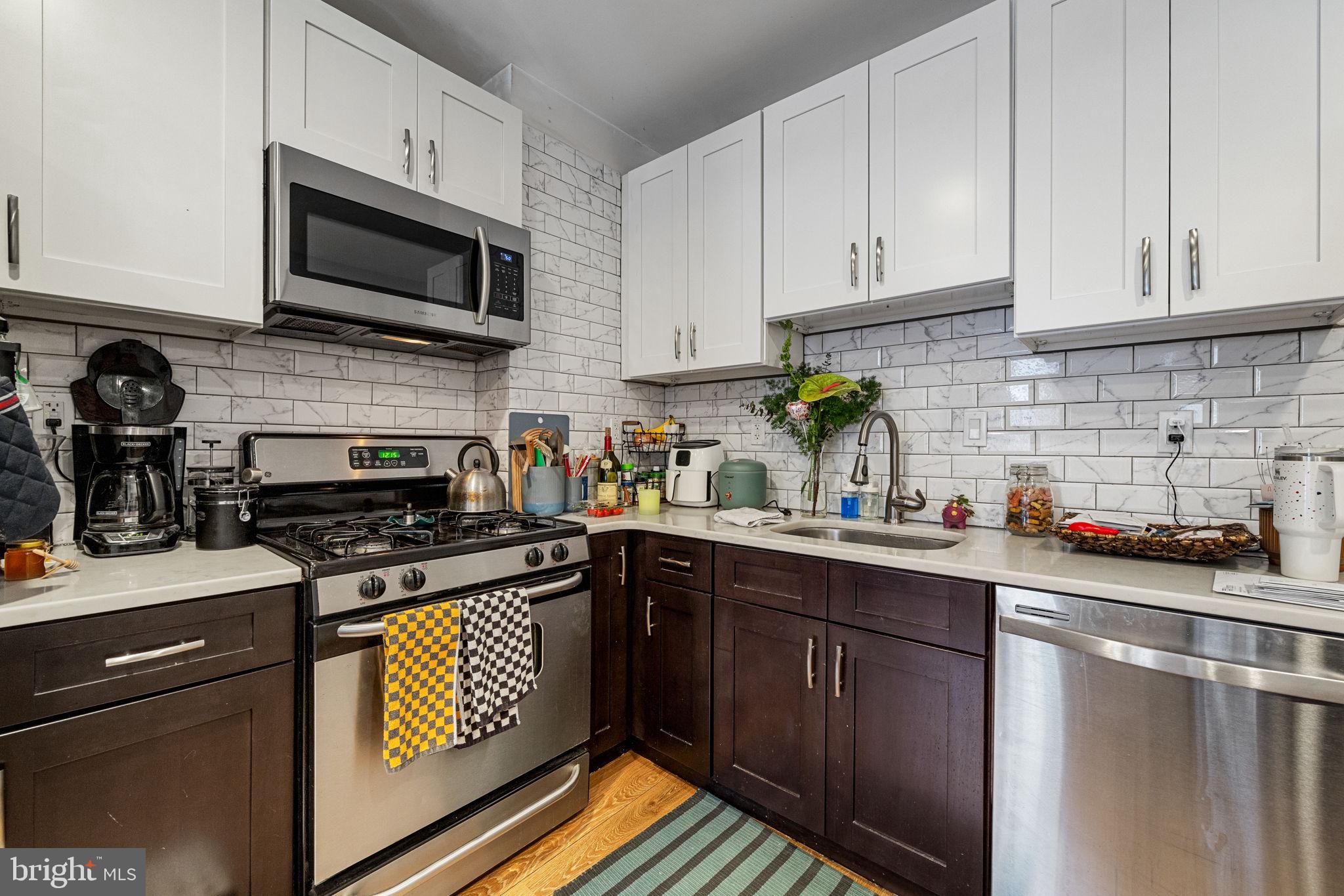 744 South 19th Street Philadelphia, PA 19146 - Photo 22 of 29 a kitchen with stainless steel appliances granite countertop a stove top oven a sink dishwasher and cabinets with wooden floor
