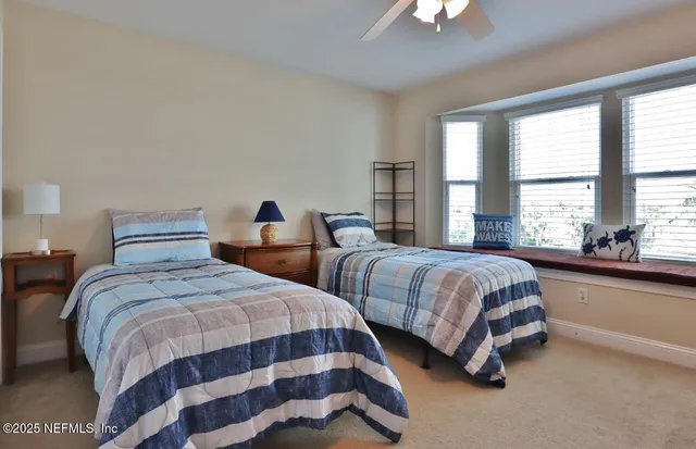 a bedroom with two beds and a chandelier next to a window