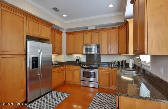 a kitchen with stainless steel appliances granite countertop a stove a sink a refrigerator and cabinets