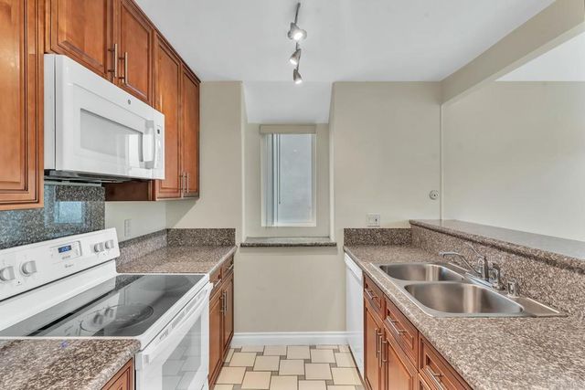 a kitchen with granite countertop a sink a stove and cabinets