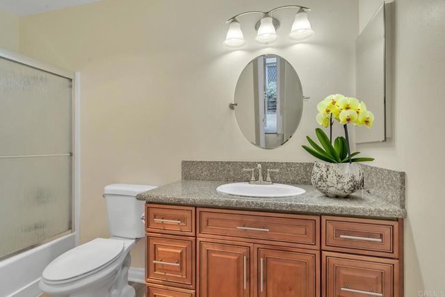 a bathroom with a granite countertop toilet sink and mirror
