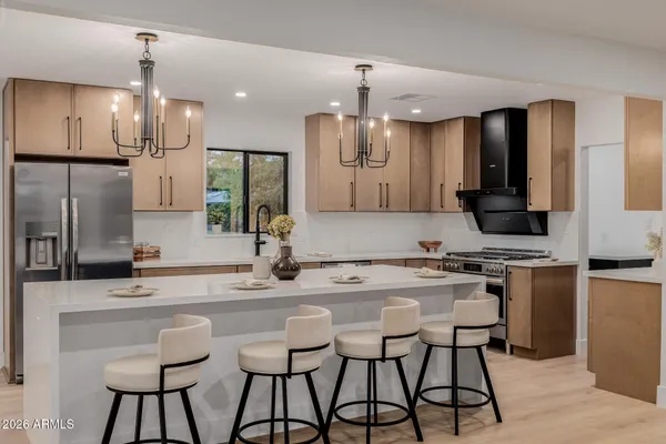 a kitchen with stainless steel appliances kitchen island granite countertop a sink a stove a refrigerator and chairs