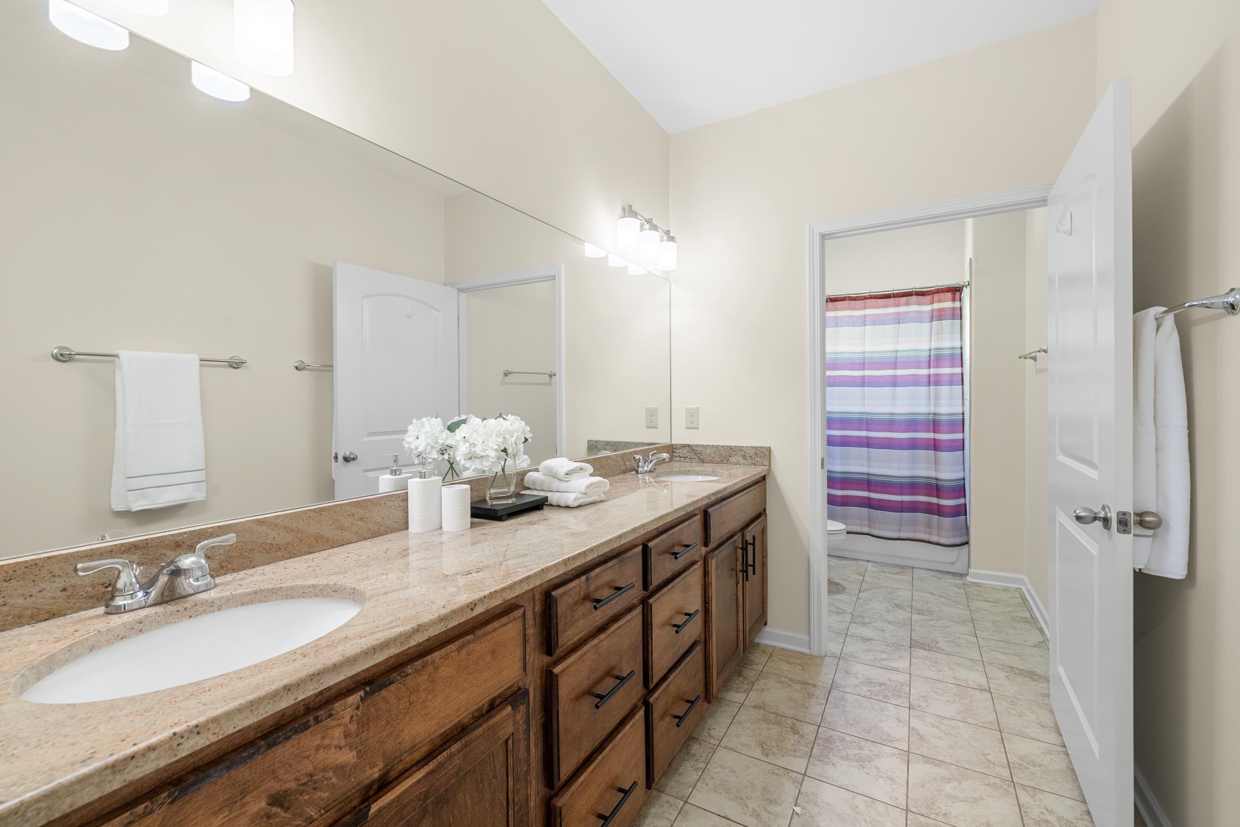 185 Belmont Road Mason, TN 38049 - Photo 25 of 38 Dual vanity with a stone-finish countertop, undermount sinks, and wood-finish cabinetry