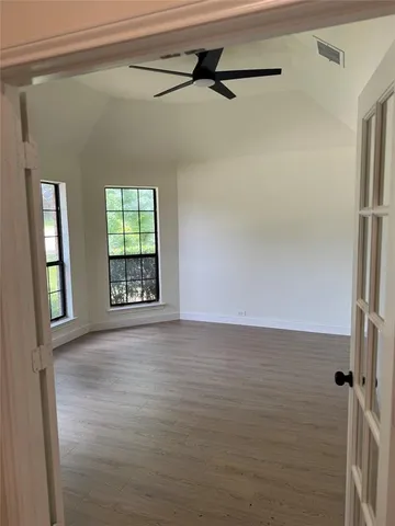 an empty room with wooden floor and windows