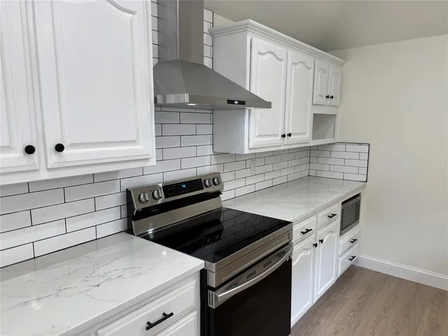 a kitchen with granite countertop white cabinets and stainless steel appliances