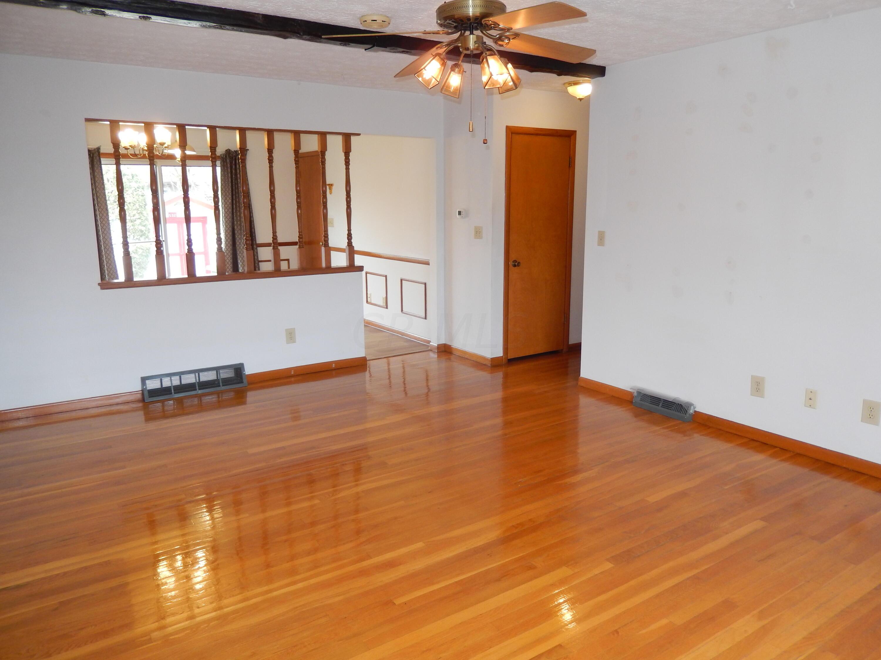 Living Room with beautiful hardwood floors and a ceiling fan opens to Kitchen area