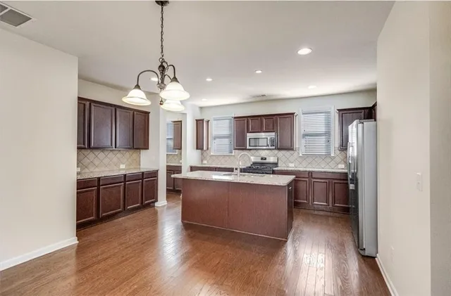 a large kitchen with stainless steel appliances granite countertop a sink stove and refrigerator