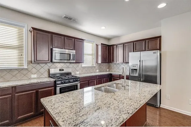 a kitchen with stainless steel appliances granite countertop a kitchen island hardwood floor sink stove and microwave