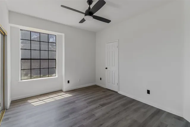 an empty room with wooden floor cabinet and windows
