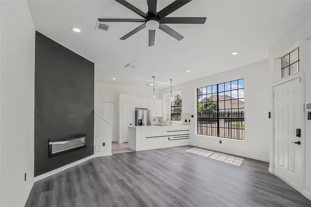 a view of an empty room with a window and a kitchen
