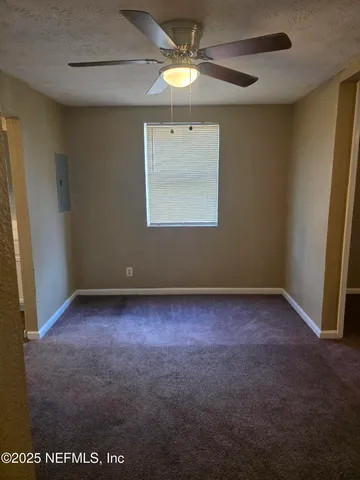an empty room with a fan & a window