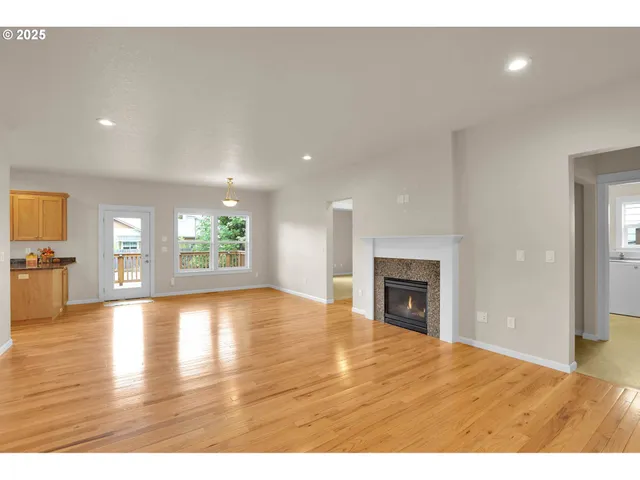 a view of an empty room with window and wooden floor