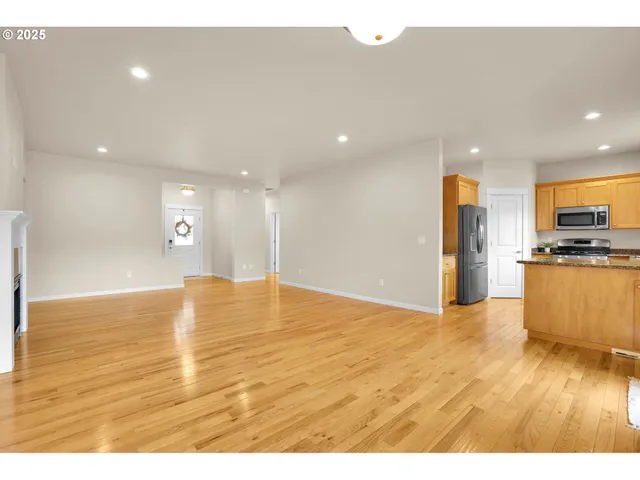a view of kitchen and empty room with wooden floor