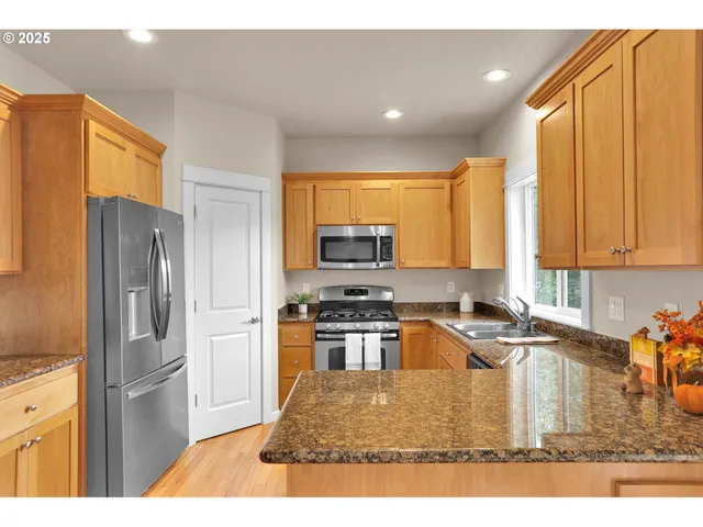 a kitchen with a refrigerator a stove top oven cabinetry a sink and a window