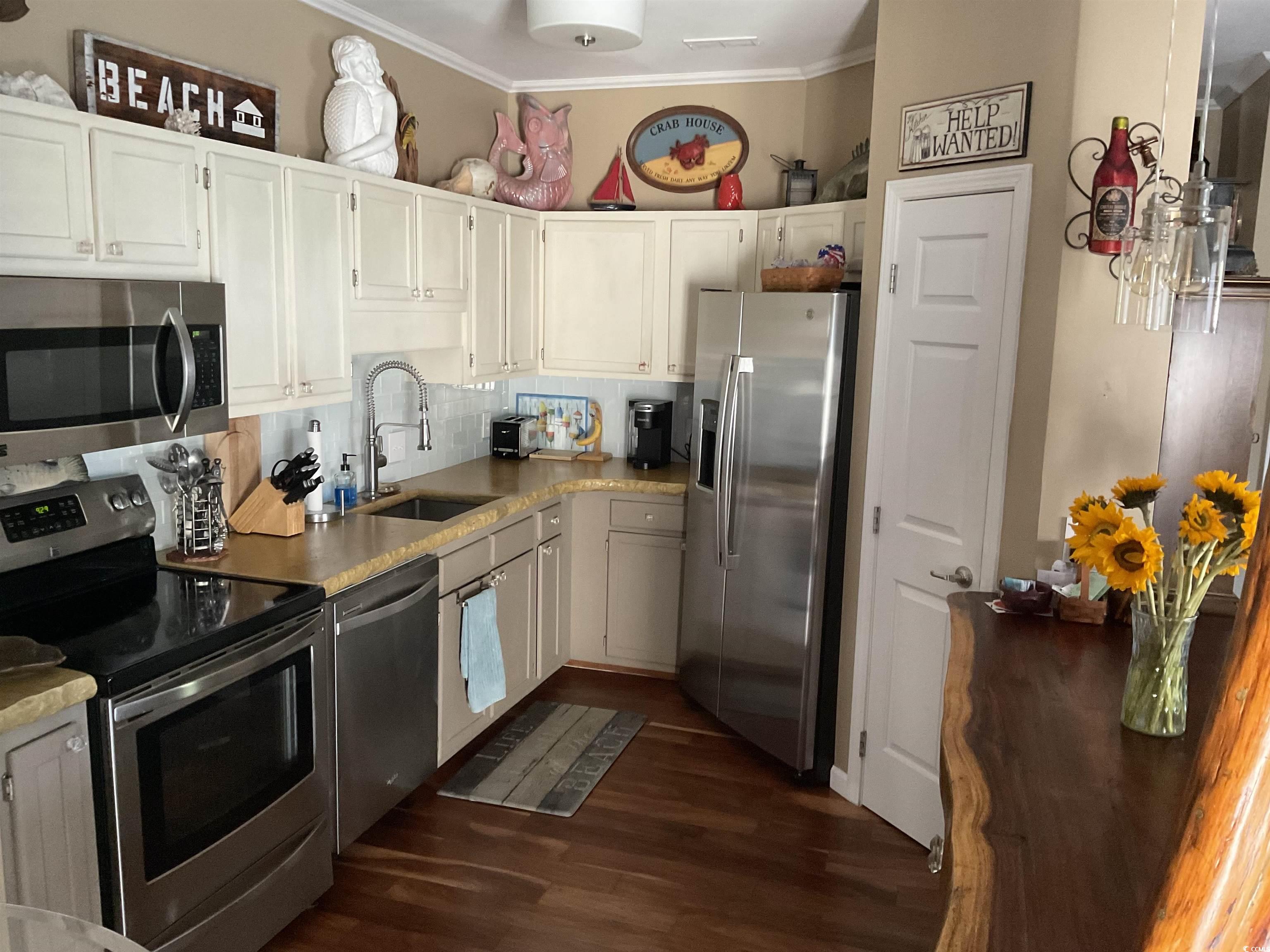 804 Brenda Place Myrtle Beach, SC 29577 - Photo 8 of 39 Kitchen with appliances with stainless steel finishes, ornamental molding, dark wood-type flooring, tasteful backsplash, and white cabinets