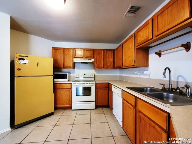 a kitchen with a refrigerator sink and cabinets