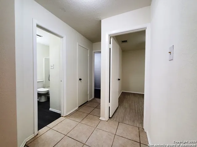 a view of a hallway with closet and a bathroom