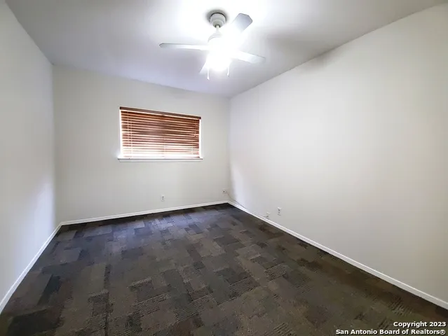 an empty room with a window and a ceiling fan