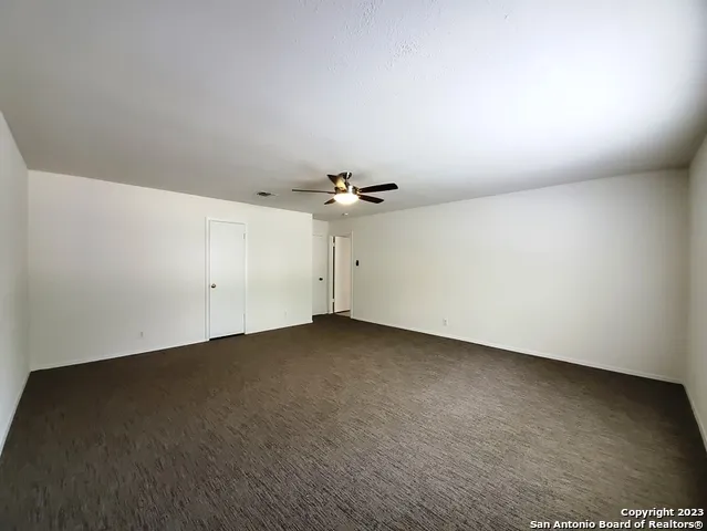 an empty room with ceiling fan and window
